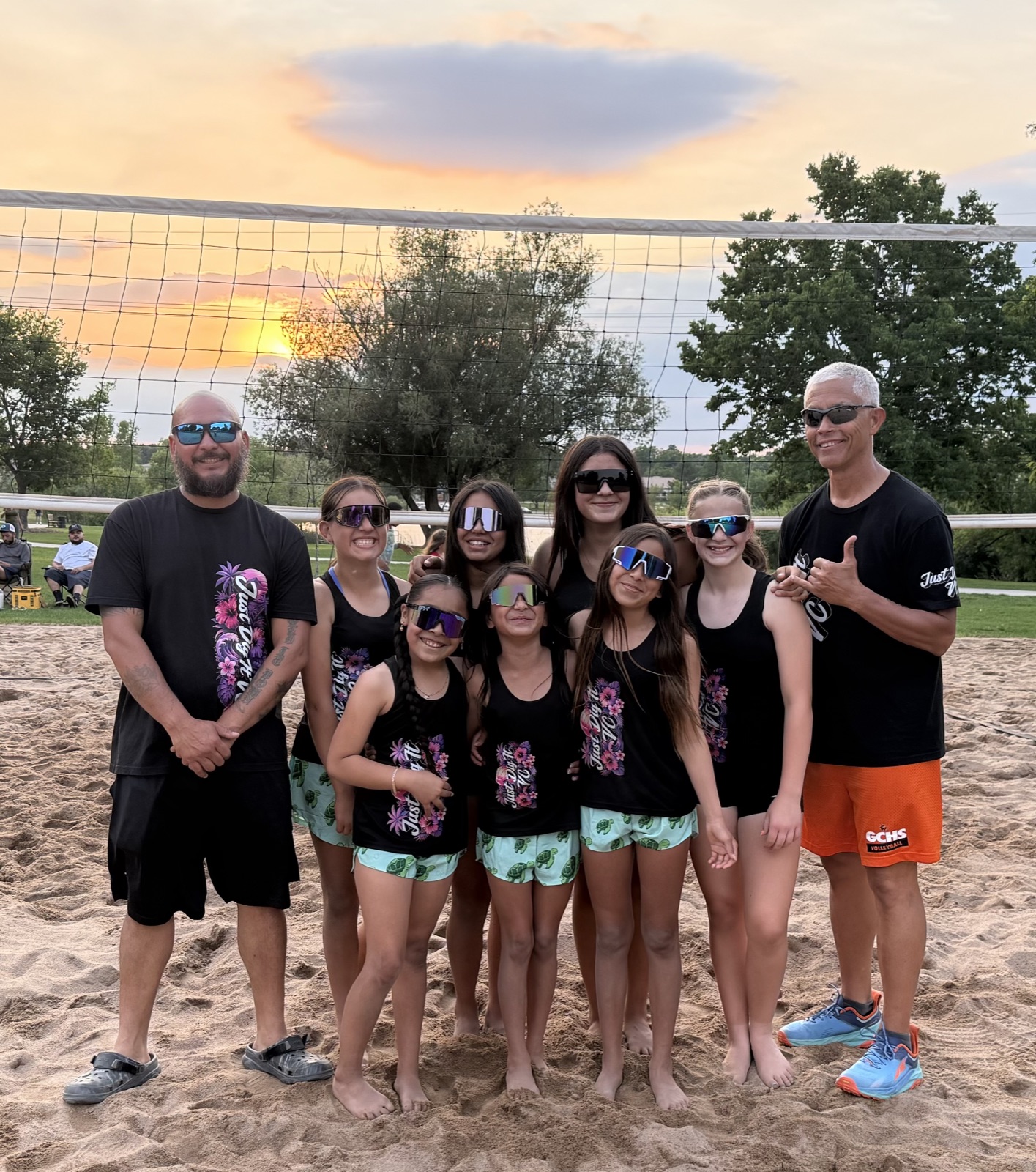 Just Dig It VC Beach team with their coaches by the net at sunset